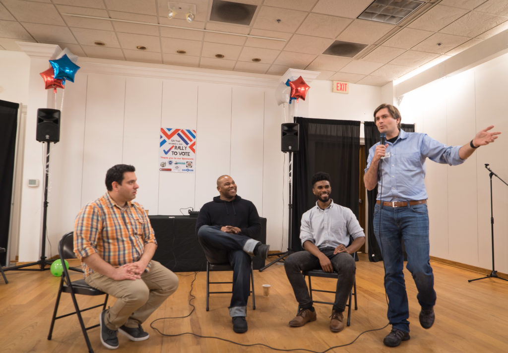 Organizers Martin Moore, Shyan Selah and Jesse Johnson look on as WA State rep Mike Pelliciotti addresses audience.