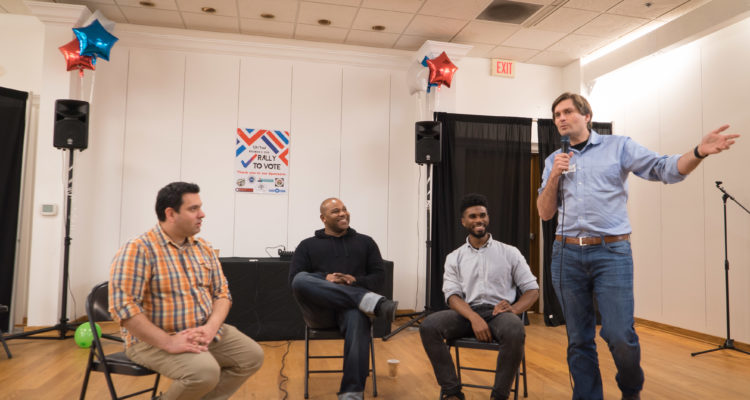 Organizers Martin Moore, Shyan Selah and Jesse Johnson look on as WA State rep Mike Pelliciotti addresses audience.